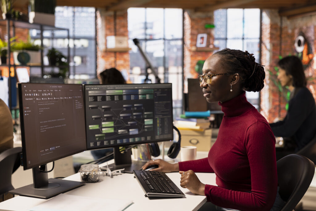 Computer scientist in startup office designing, coding and debugging applications in different software languages. African american woman doing code testing and quality assurance